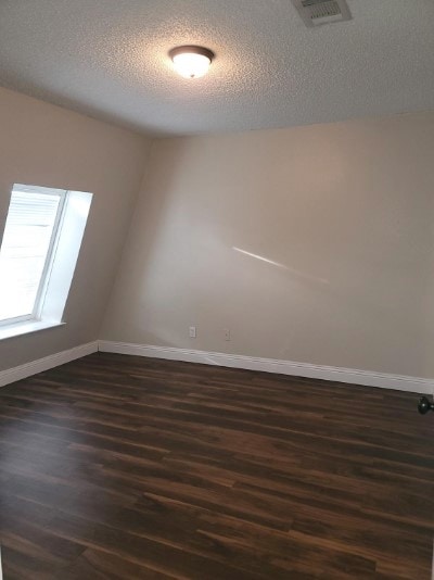 unfurnished room featuring dark wood-type flooring and a textured ceiling