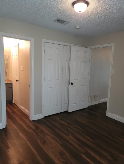 unfurnished bedroom featuring dark wood-type flooring, a closet, and a textured ceiling