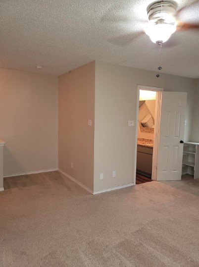 carpeted empty room featuring a textured ceiling and ceiling fan