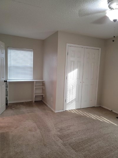 unfurnished bedroom with a closet, a textured ceiling, carpet, and ceiling fan