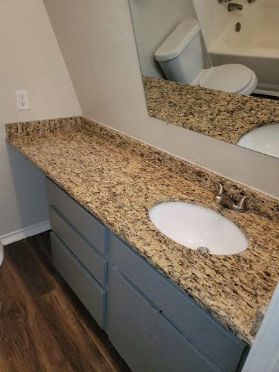 bathroom featuring vanity, a bathing tub, toilet, and hardwood / wood-style floors