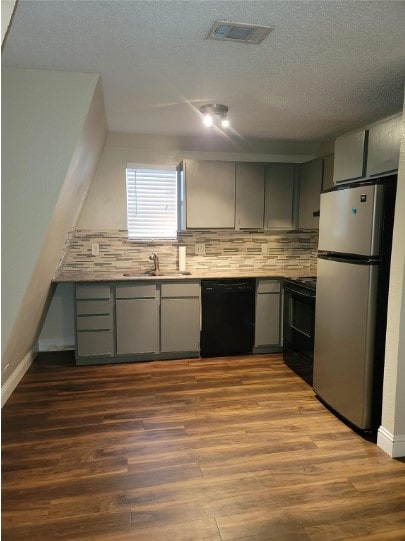 kitchen with gray cabinetry, black appliances, sink, backsplash, and light hardwood / wood-style floors