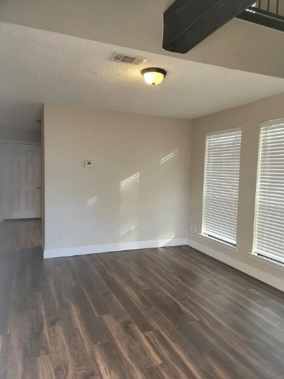 spare room with a textured ceiling and dark wood-type flooring