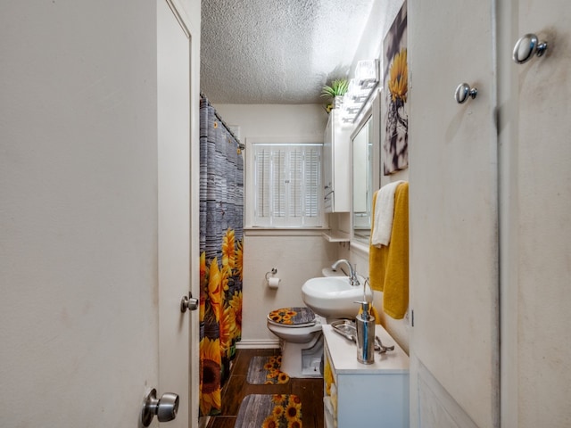 bathroom featuring hardwood / wood-style flooring, toilet, a shower with curtain, vanity, and a textured ceiling