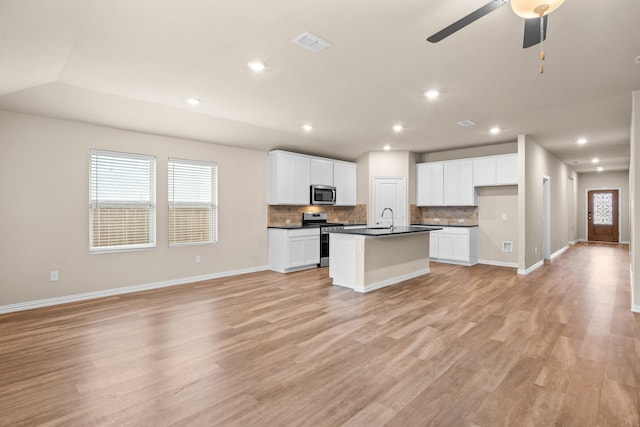 kitchen with light wood-type flooring, a kitchen island with sink, stainless steel appliances, and white cabinets