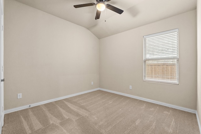 carpeted spare room featuring vaulted ceiling and ceiling fan