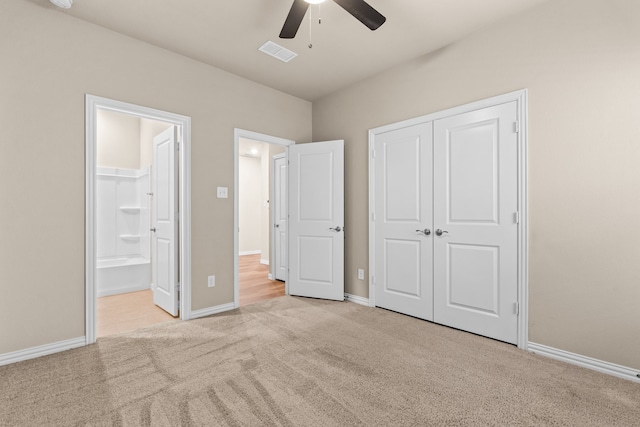 unfurnished bedroom featuring connected bathroom, light colored carpet, a closet, and ceiling fan