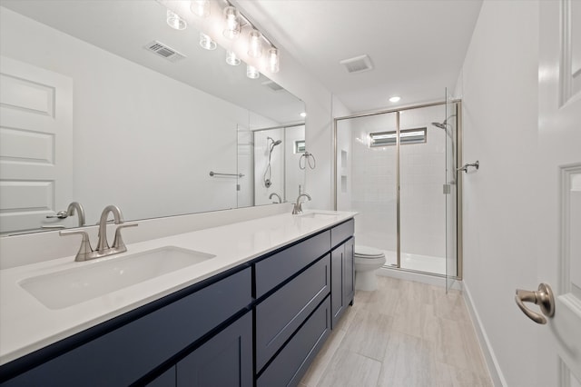 bathroom featuring toilet, vanity, and a shower with door