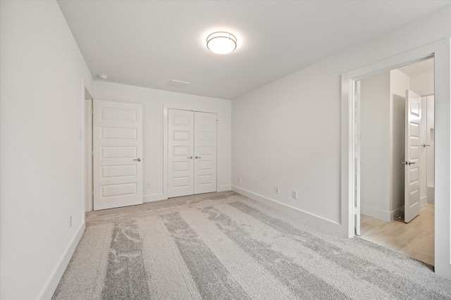 unfurnished bedroom featuring connected bathroom, light carpet, and a closet