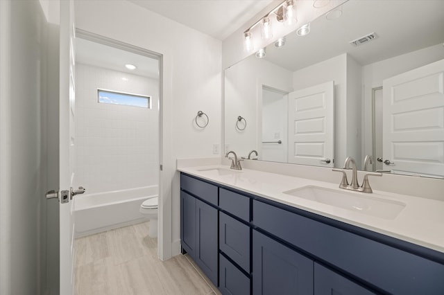 full bathroom with vanity, tiled shower / bath combo, and toilet