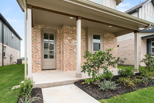 view of exterior entry with central AC, a yard, and covered porch