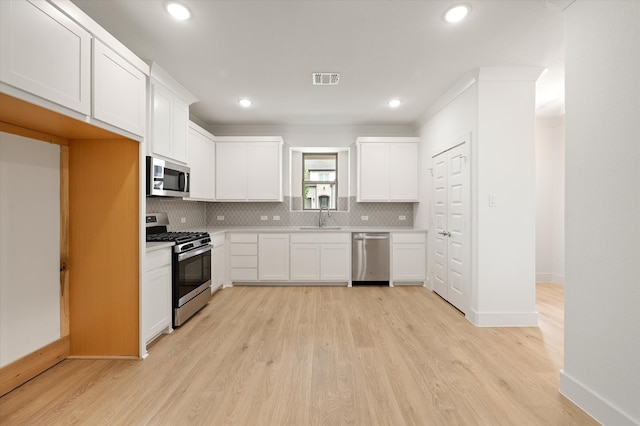 kitchen with appliances with stainless steel finishes, white cabinets, and light wood-type flooring