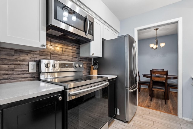 kitchen featuring an inviting chandelier, hanging light fixtures, stainless steel appliances, decorative backsplash, and white cabinets