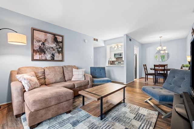 living room with wood-type flooring, sink, and a notable chandelier