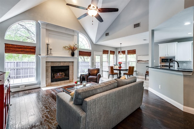 living room with plenty of natural light, dark hardwood / wood-style floors, a tile fireplace, and high vaulted ceiling