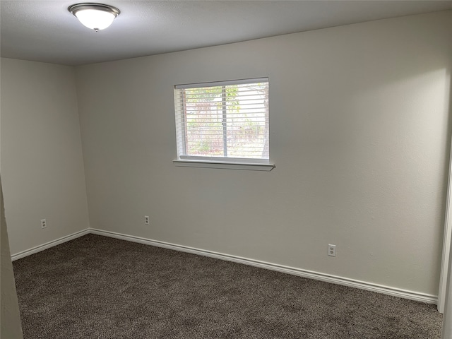 spare room with dark carpet