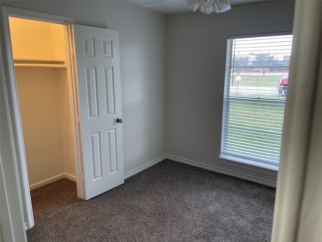 unfurnished bedroom with dark carpet, a spacious closet, and a closet