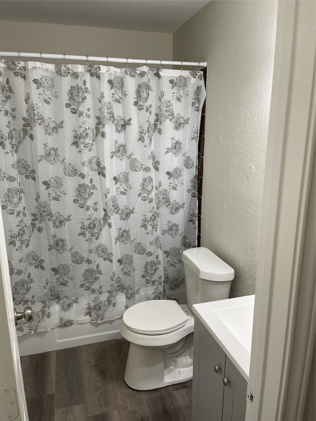 full bathroom with vanity, toilet, wood-type flooring, and shower / tub combo