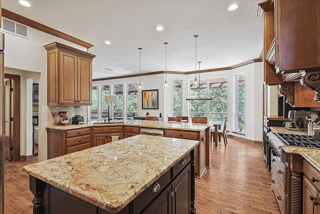 kitchen featuring wood-type flooring, decorative light fixtures, a kitchen island, and ornamental molding