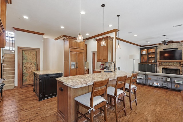 kitchen with dark hardwood / wood-style floors, kitchen peninsula, a center island, light stone counters, and ceiling fan