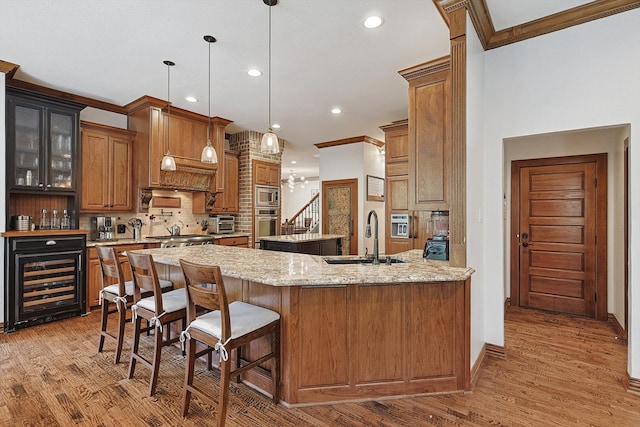 kitchen featuring light stone countertops, sink, hanging light fixtures, and light wood-type flooring