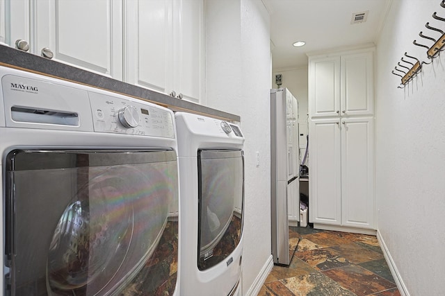 clothes washing area featuring washer and dryer and cabinets