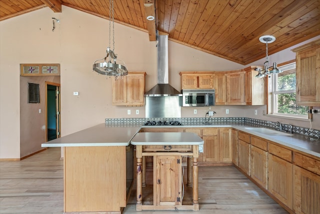 kitchen with sink, an inviting chandelier, a kitchen island, decorative light fixtures, and wall chimney exhaust hood