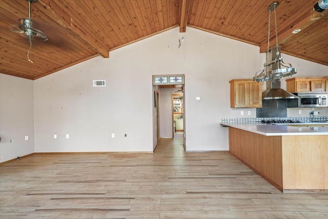 kitchen with decorative light fixtures, kitchen peninsula, light wood-type flooring, and wall chimney range hood