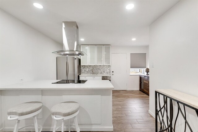 11306 Park Central Pl Unit D, Dallas, TX 75230 - kitchen featuring island range hood, freestanding refrigerator, black electric cooktop, white cabinetry, and a sink