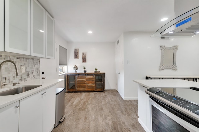 kitchen with extractor fan, sink, stainless steel electric range, white cabinetry, and light hardwood / wood-style floors