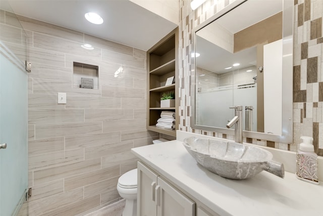 bathroom with vanity, toilet, tile walls, and walk in shower