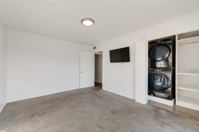 clothes washing area featuring stacked washing maching and dryer and carpet floors