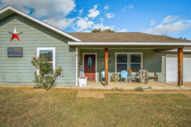 view of front of property with a porch, a front yard, and a garage