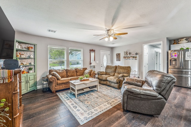 living room featuring dark wood-type flooring, a textured ceiling, and ceiling fan