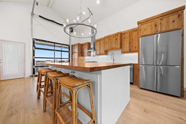 kitchen with stainless steel fridge, a kitchen island, a notable chandelier, a kitchen bar, and decorative light fixtures