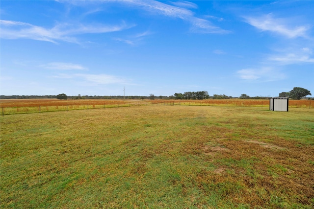 view of yard with a shed and a rural view