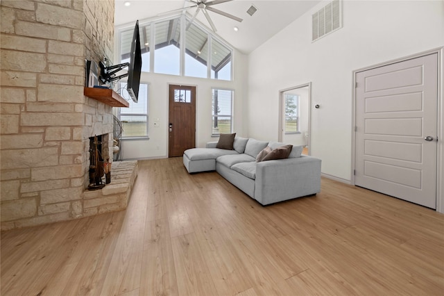 unfurnished living room featuring a fireplace, light hardwood / wood-style floors, ceiling fan, and high vaulted ceiling