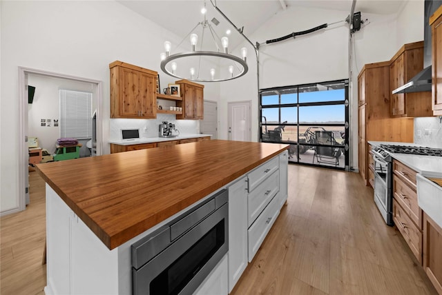 950 Vz County Road 1604, Grand Saline, TX 75140 - kitchen with butcher block countertops, high vaulted ceiling, stainless steel appliances, open shelves, and wall chimney range hood
