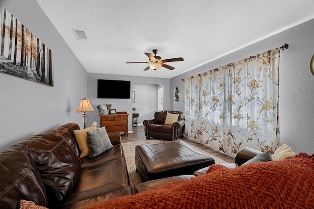 living room with ceiling fan, hardwood / wood-style flooring, and a textured ceiling