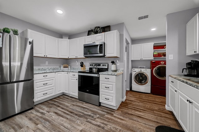 kitchen featuring white cabinetry, appliances with stainless steel finishes, wood-type flooring, and washing machine and clothes dryer