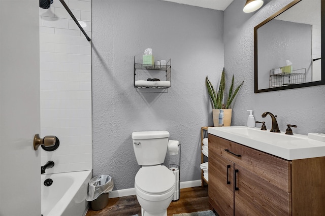 full bathroom featuring tiled shower / bath, vanity, hardwood / wood-style floors, and toilet