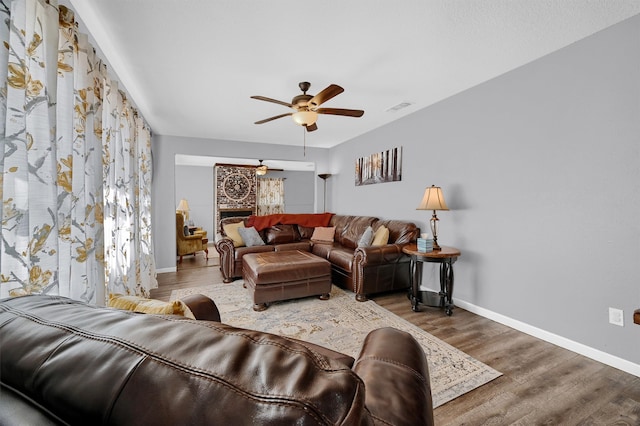 living room with a fireplace, hardwood / wood-style flooring, and ceiling fan