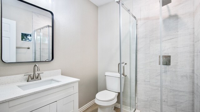 bathroom with toilet, vanity, and a shower with door