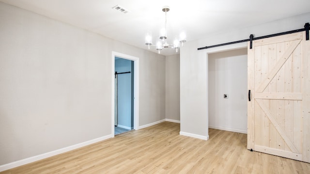 interior space featuring a closet, light hardwood / wood-style flooring, a barn door, and an inviting chandelier