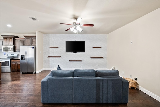 living room with dark hardwood / wood-style floors, ceiling fan, and brick wall