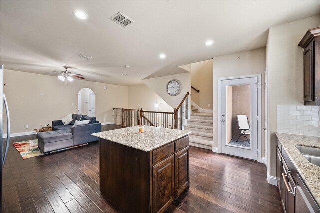 kitchen with a center island, dark hardwood / wood-style floors, light stone counters, and backsplash