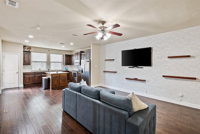 living room with ceiling fan, sink, brick wall, and dark hardwood / wood-style floors