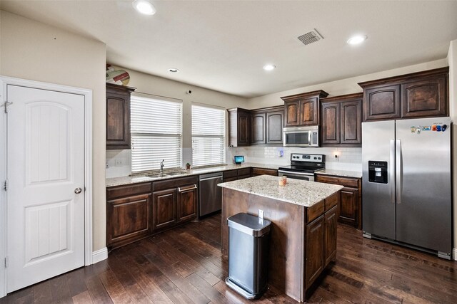 kitchen with dark brown cabinetry, sink, a kitchen island, and appliances with stainless steel finishes