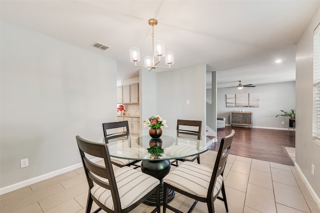 dining space featuring light wood-type flooring and ceiling fan with notable chandelier