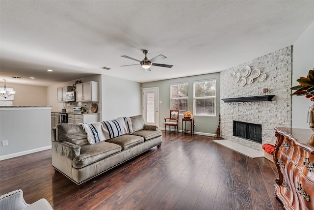 living room with a textured ceiling, a fireplace, ceiling fan with notable chandelier, and dark hardwood / wood-style flooring